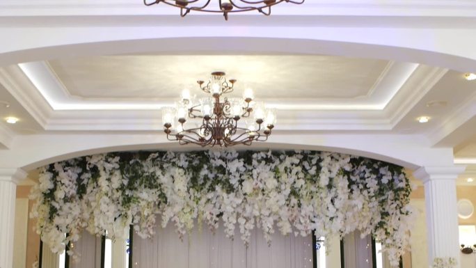 婚礼宴会厅的内部，从枝形吊灯俯瞰摆满蜡烛和食物的宴会桌。美丽的装饰