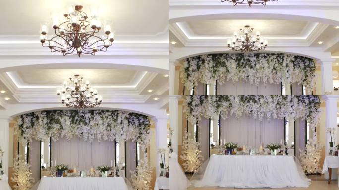 婚礼宴会厅的内部，从枝形吊灯俯瞰摆满蜡烛和食物的宴会桌。美丽的装饰