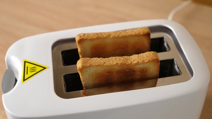烤好的面包从电烤面包机里跳出来。
