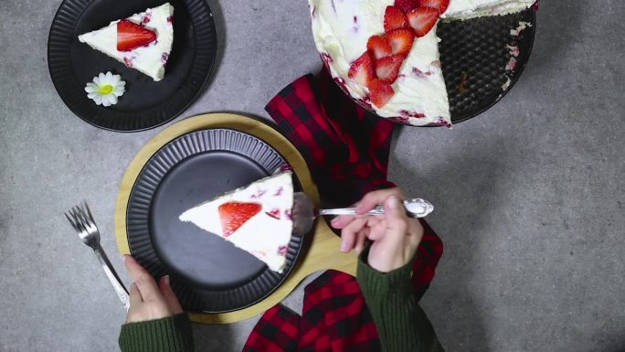 一名妇女正在用黑色盘子端上一份草莓蛋糕或法语Fraisier