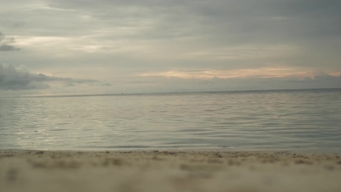 热带岛屿上的沙滩。海浪冲刷着海岸。背景是日落时的乌云。马尔代夫。