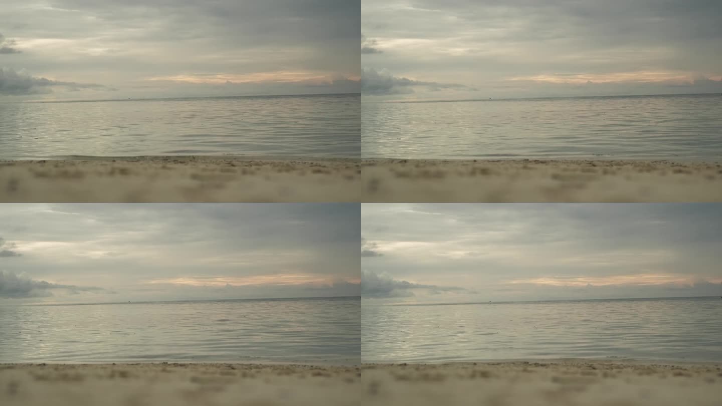 热带岛屿上的沙滩。海浪冲刷着海岸。背景是日落时的乌云。马尔代夫。