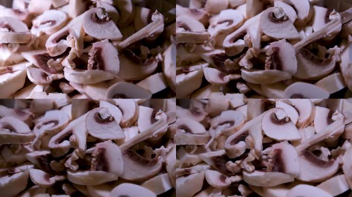 盘子里有大量切碎的蘑菇。蘑菇堆上落了几块冠军。坠落的慢动作。烹饪美食的美丽镜头。