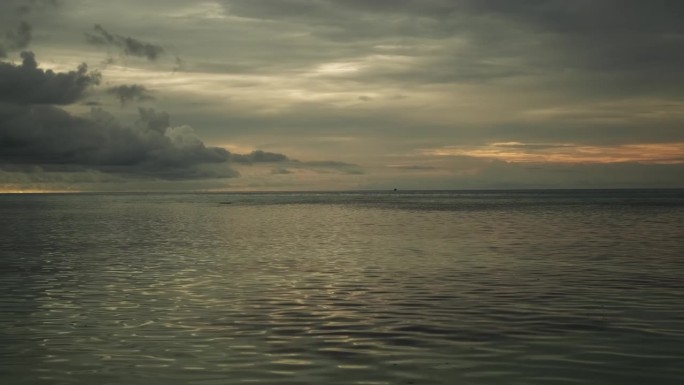 日落时平静的海浪。美丽的暴风雨前多云的天空为背景。