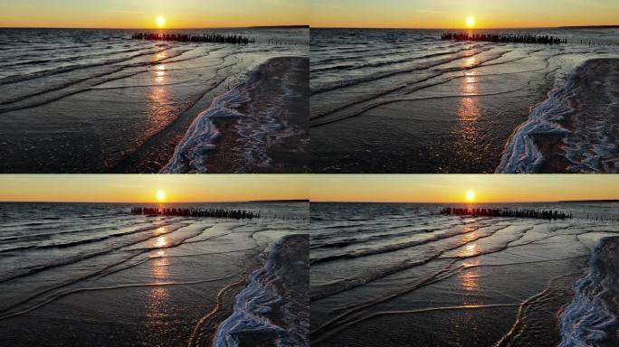 古老的码头，平静的海面上美丽的日落。天空闪耀着炽热的橙色、粉红色和紫色，太阳是一个发光的圆盘，刚刚沉