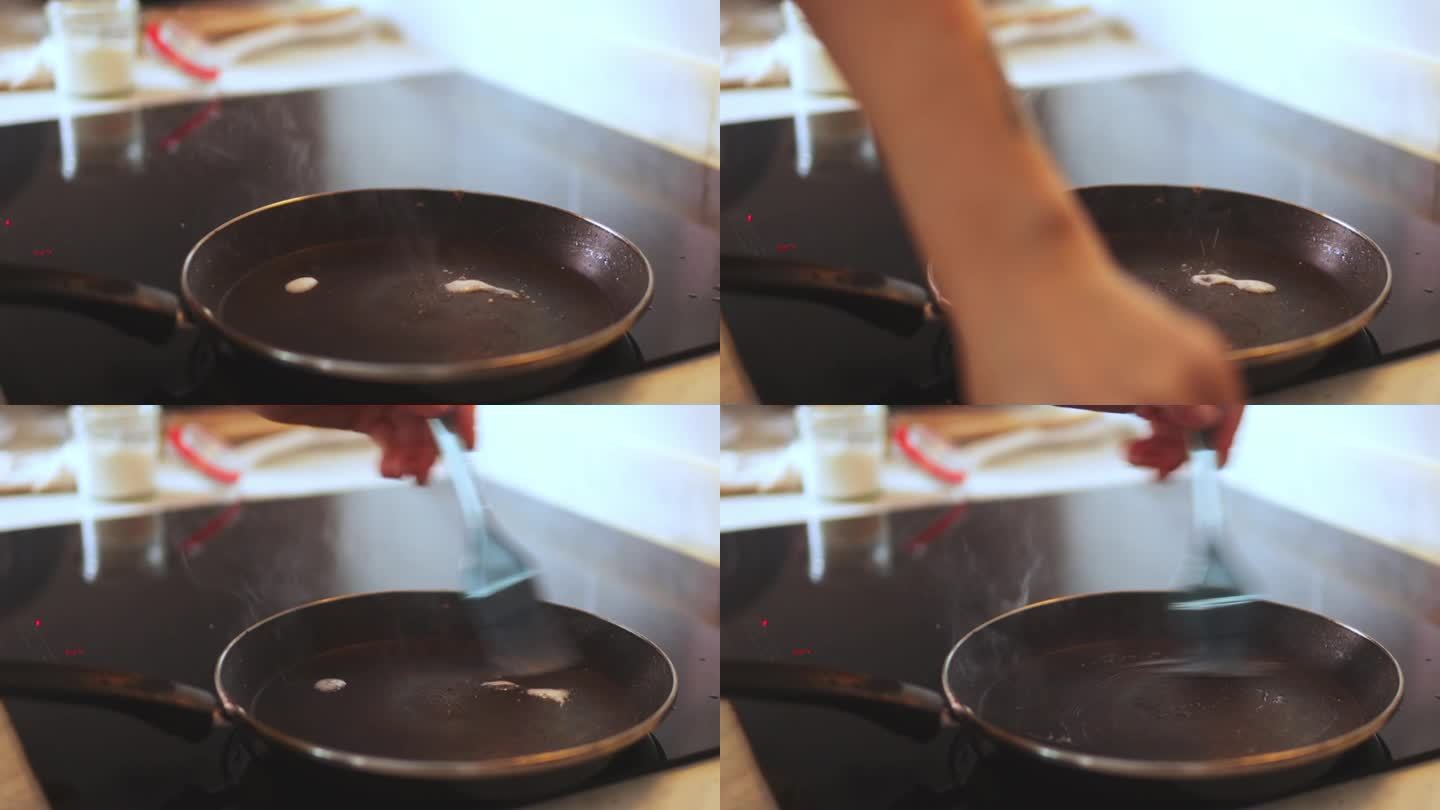 一位女士用手将油滴入滋滋作响的煎锅中，在准备美味佳肴时，厨房里充满了开胃的香味。