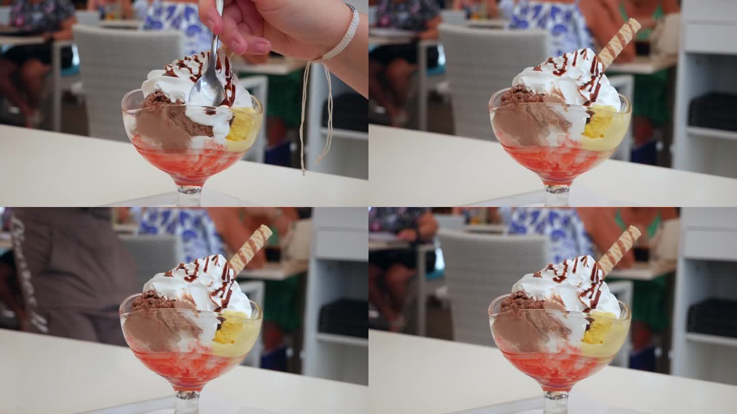 在一家咖啡馆里，一只手用勺子舀进奶油味的巧克力冰淇淋圣代，用勺子挑逗味蕾，这是美食博客和甜点营销的理