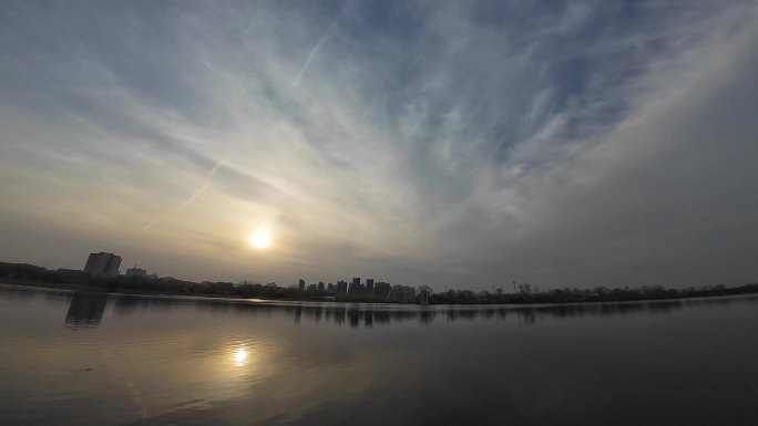 夕阳下的水面宽阔静美沿岸建筑树木倒映水面