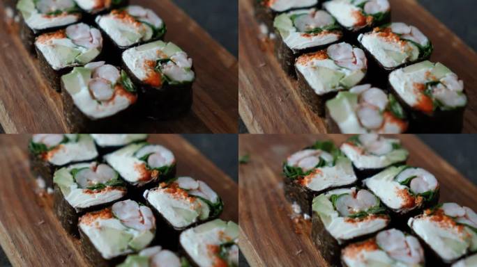 日本食物，有米饭、红生鱼、奶油奶酪、鲑鱼、虾、鳄梨和海苔。桌上摆着开胃的寿司卷。寿司厨师提供的美味又