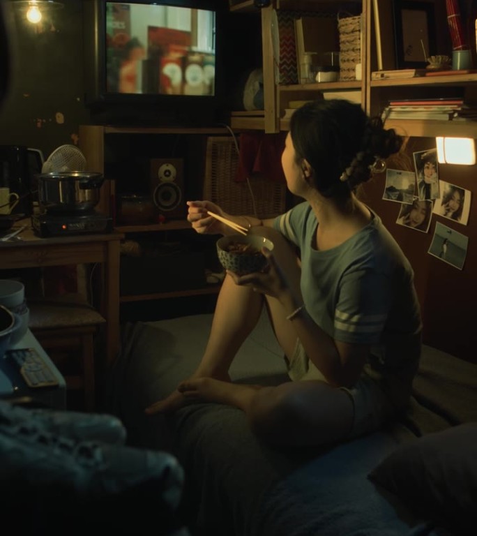 韩国女孩在微公寓吃炒菜和看电视广告