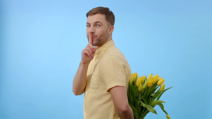 一个男人手里拿着一大束明黄色的花。花朵充满活力，与男人的衣服形成鲜明对比