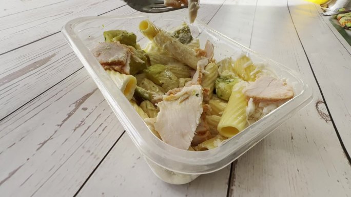 一份现成的健康食品，放在一次性午餐盒里，配上火腿、磨碎的奶酪和意大利面，作为每天的饮食计划，用叉子快