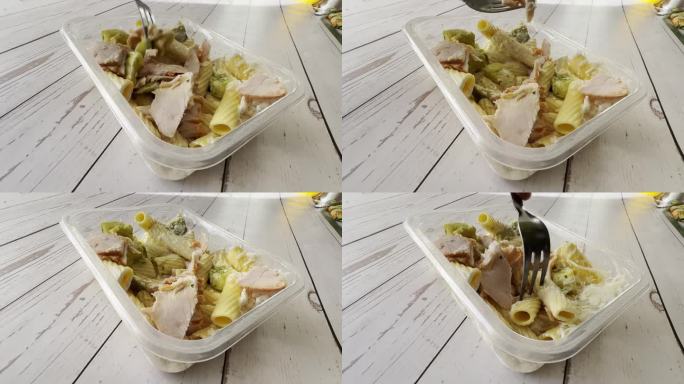 一份现成的健康食品，放在一次性午餐盒里，配上火腿、磨碎的奶酪和意大利面，作为每天的饮食计划，用叉子快