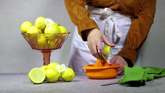 女性的手在橙色塑料挤压机上挤压新鲜的柠檬汁