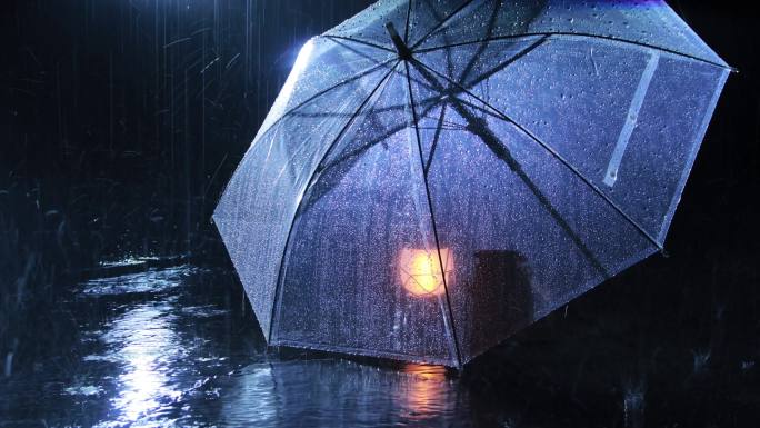 车灯前大雨中的雨伞