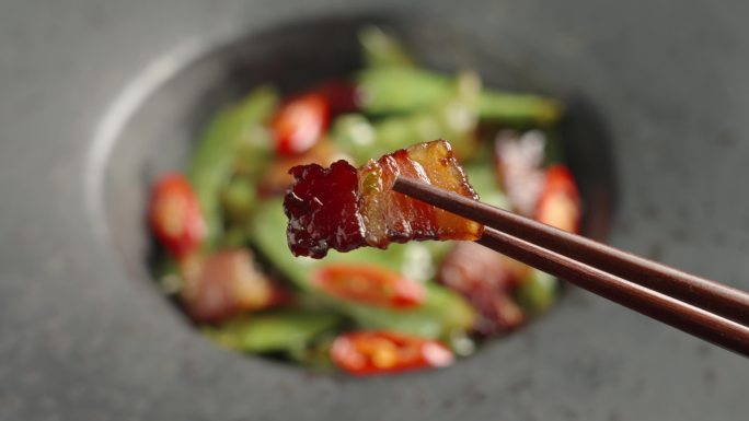 筷子夹起一片腊肉美食特写