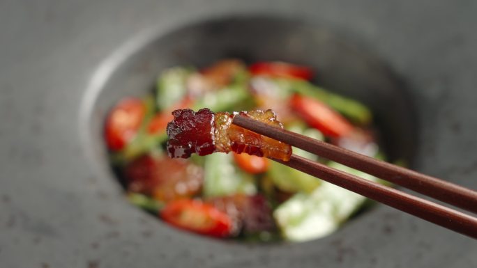 筷子夹起一片腊肉美食特写