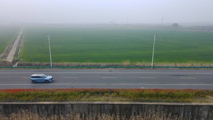 无人机跟随汽车在田野边的路上行驶