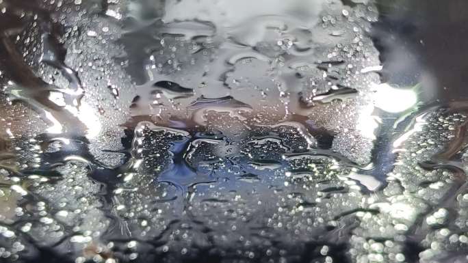 雨点滴在挡风玻下雨水珠流走雨点打在玻璃上