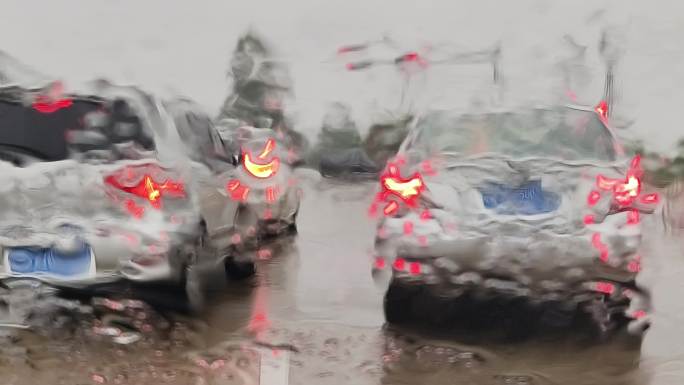 等红绿灯的车辆挡风玻下雨水珠雨点打在玻璃