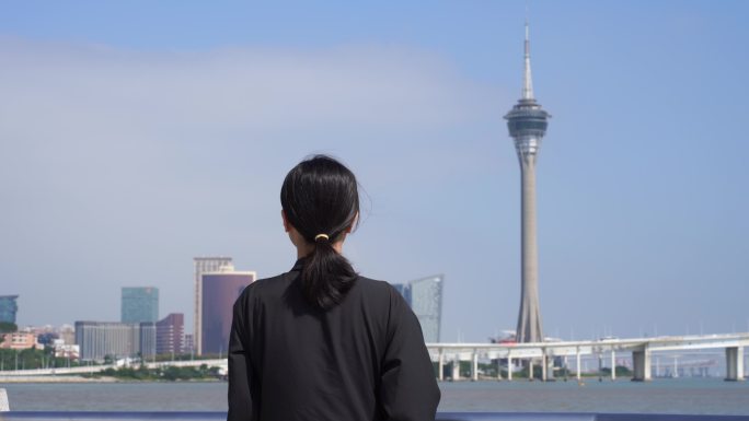 游客站在海岸边看澳门城市风景观望澳门塔