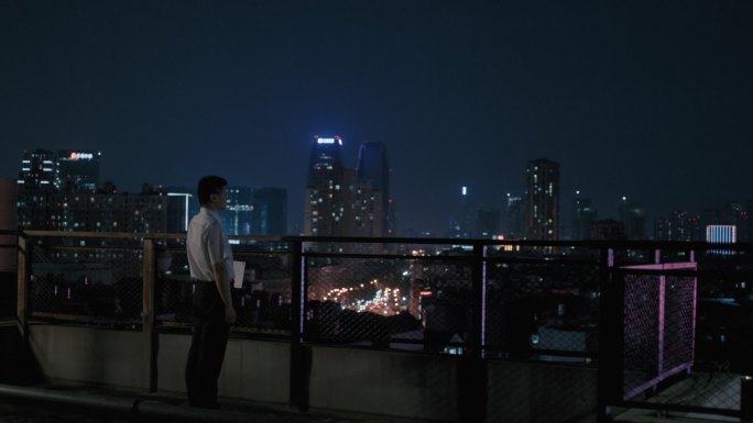 C商务男在夜晚俯瞰城市