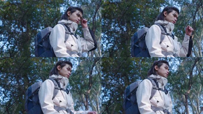 男人背包穿越树林擦汗休息