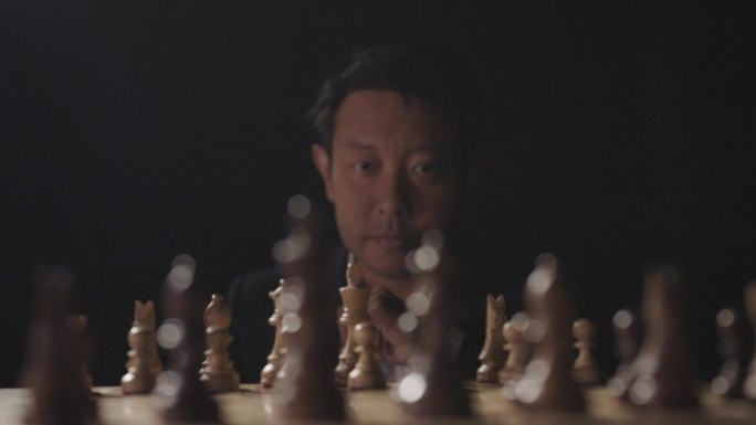 男人坐在国际象棋棋盘前思考