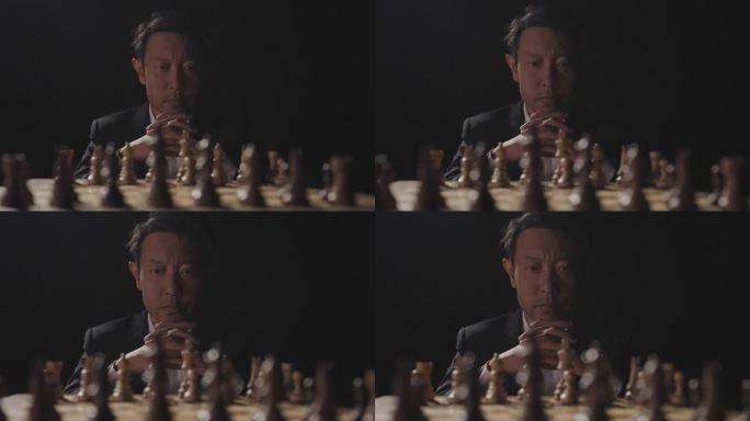 男人坐在国际象棋棋盘前观察思考
