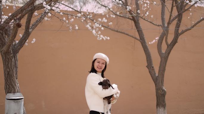 年轻女子抱着小羊羔新疆杏花村旅行