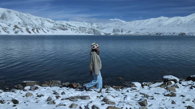 年轻女子从湖边走过徒步旅行雪山湖泊