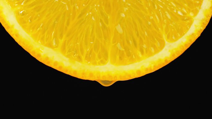 橙汁从一片橙子里滴出特写