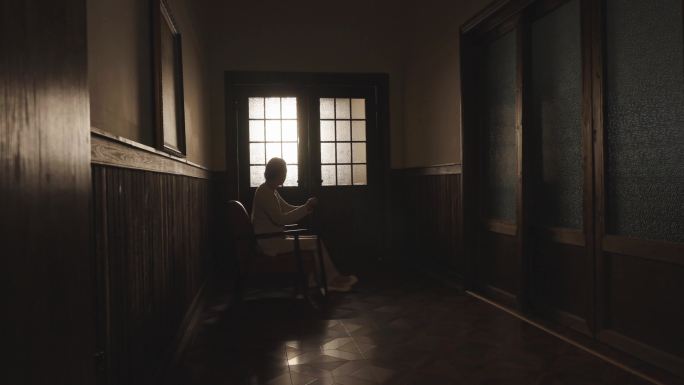 老年女人独自坐在走廊看门外