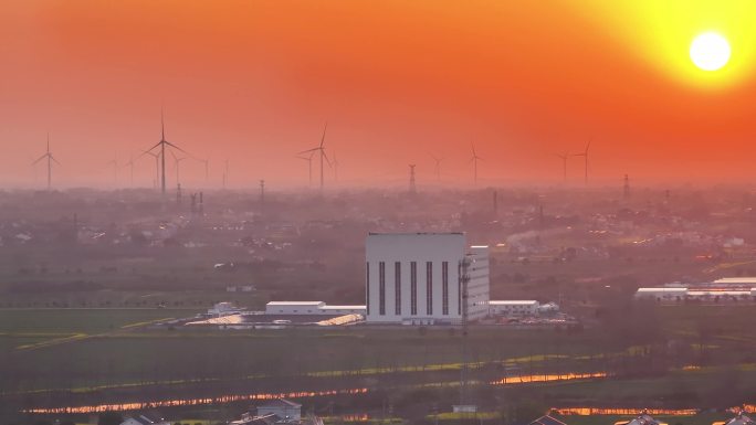 航拍夕阳落日太阳风力发电站群村庄农户平原