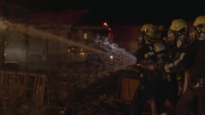 消防员在室外用高压水枪扑灭火焰