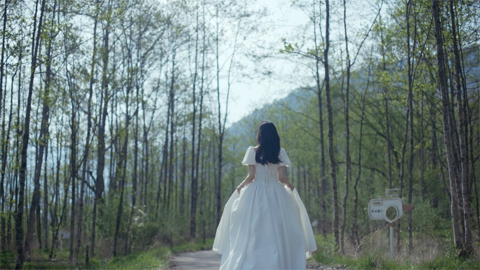 穿白色婚纱的美女奔跑在草坪上树林里