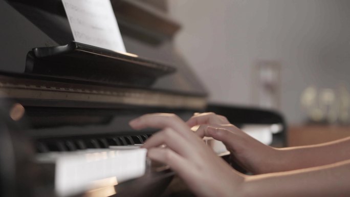 年轻女人手弹钢琴琴键特写