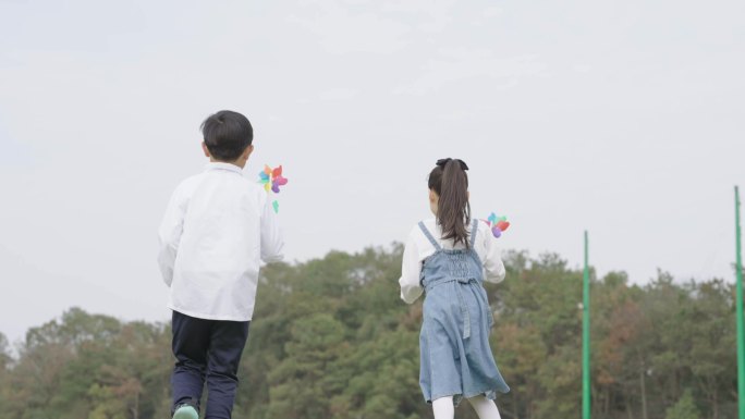 男孩女孩草地奔跑风车背影