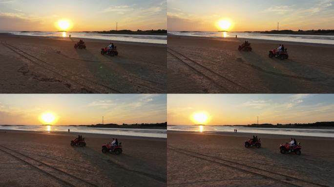 夕阳晚霞中游客在海边沙滩骑沙滩摩托