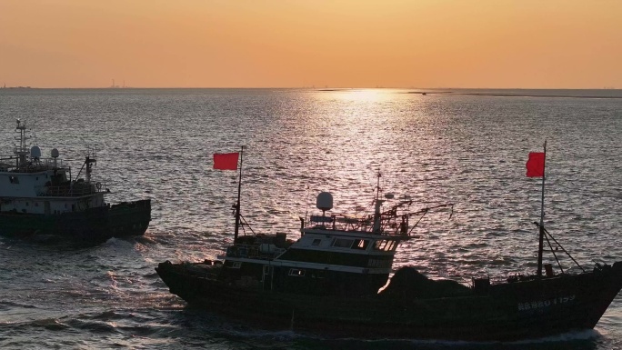 夕阳中波光粼粼的海水中渔船出海航行