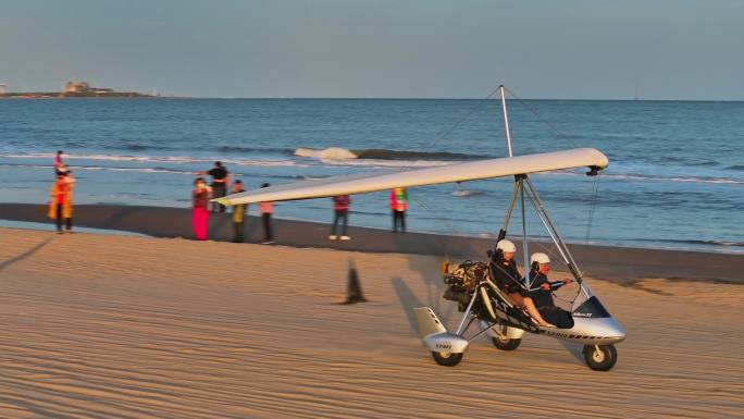 航拍4K傍晚海边海岸沙滩游客乘坐滑翔机游玩