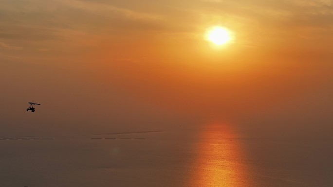 夕阳晚霞红日照射海面水面上滑翔机飞过