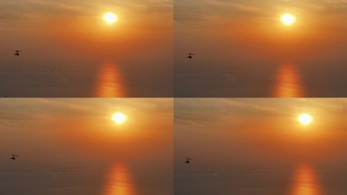 夕阳晚霞红日照射海面水面上滑翔机飞过