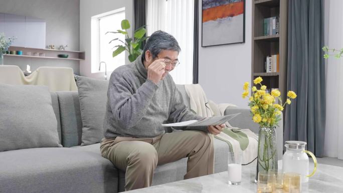 老年男人坐在客厅看报纸