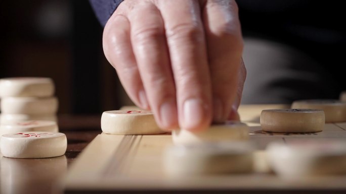 手拿象棋棋子棋盘特写