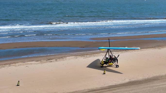 海边沙滩动力三角滑翔机载游客游玩