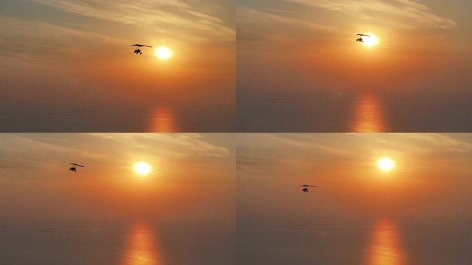 夕阳晚霞红日照射海面水面游客搭载滑翔机飞翔逆光剪影