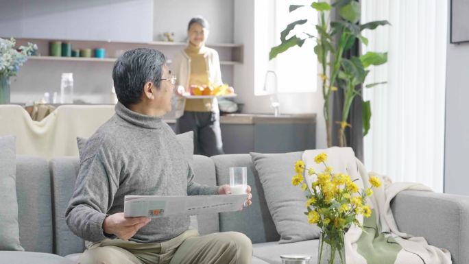 老年人两口在家里看报纸吃水果