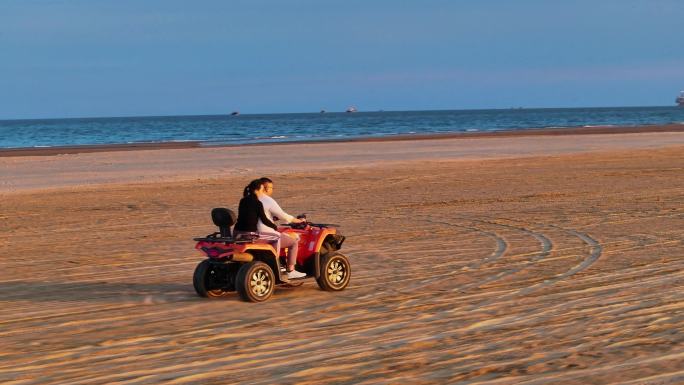 航拍4K夕阳晚霞中游客情侣在海边沙滩骑沙滩摩托
