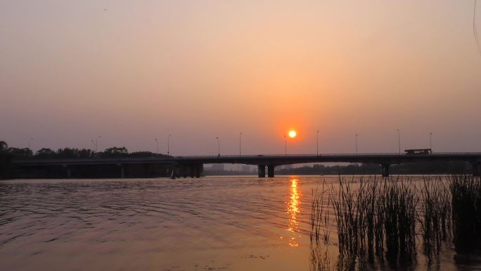 河边夕阳太阳照在水面上水天一色大桥剪影